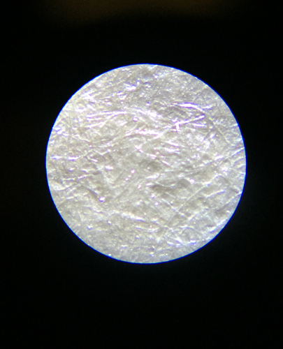 magnified surface of photograph showing lightly colored fiber of the paper