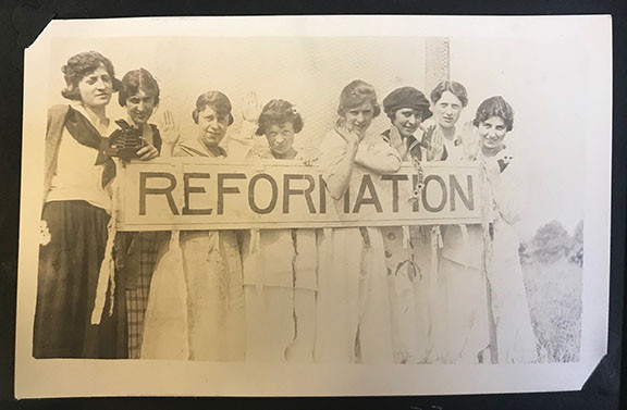 8 women hold a printed sign that says Reformation