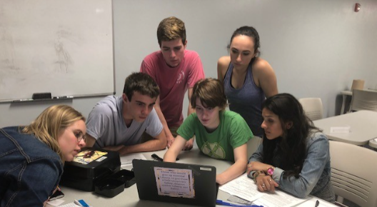 Students gathered around a laptop on a table