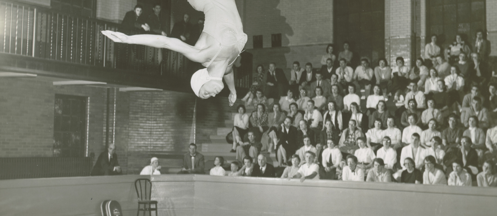 Old black and white photo of a woman diving into a pool at U of R