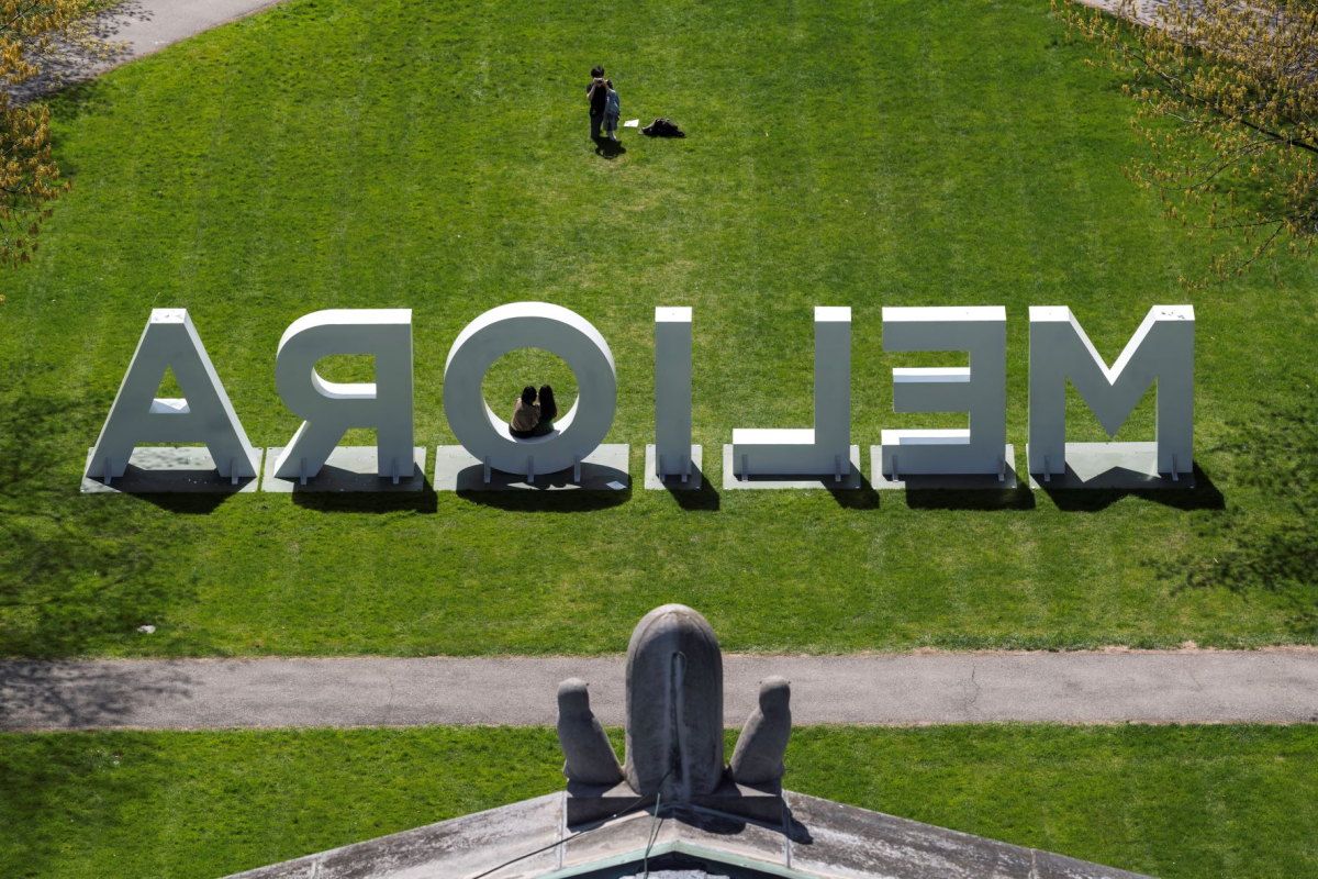 A view from behind large letters spelling out MELIORA on the Eastman Quad 