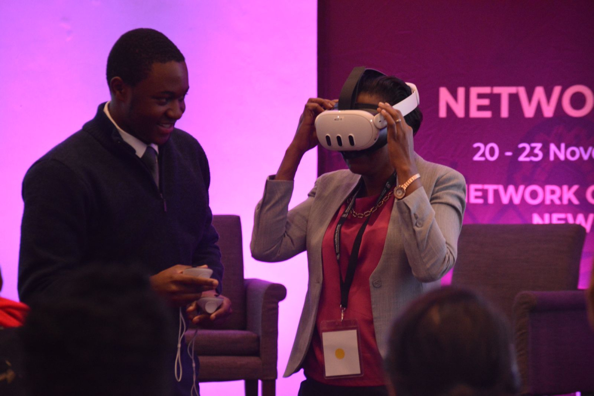 Tamuda helping a conference participant with a vr headset.