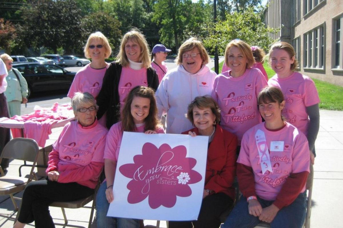 Louise Slaughter sitting among a group of women dressed in pink in support of breast cancer awareness