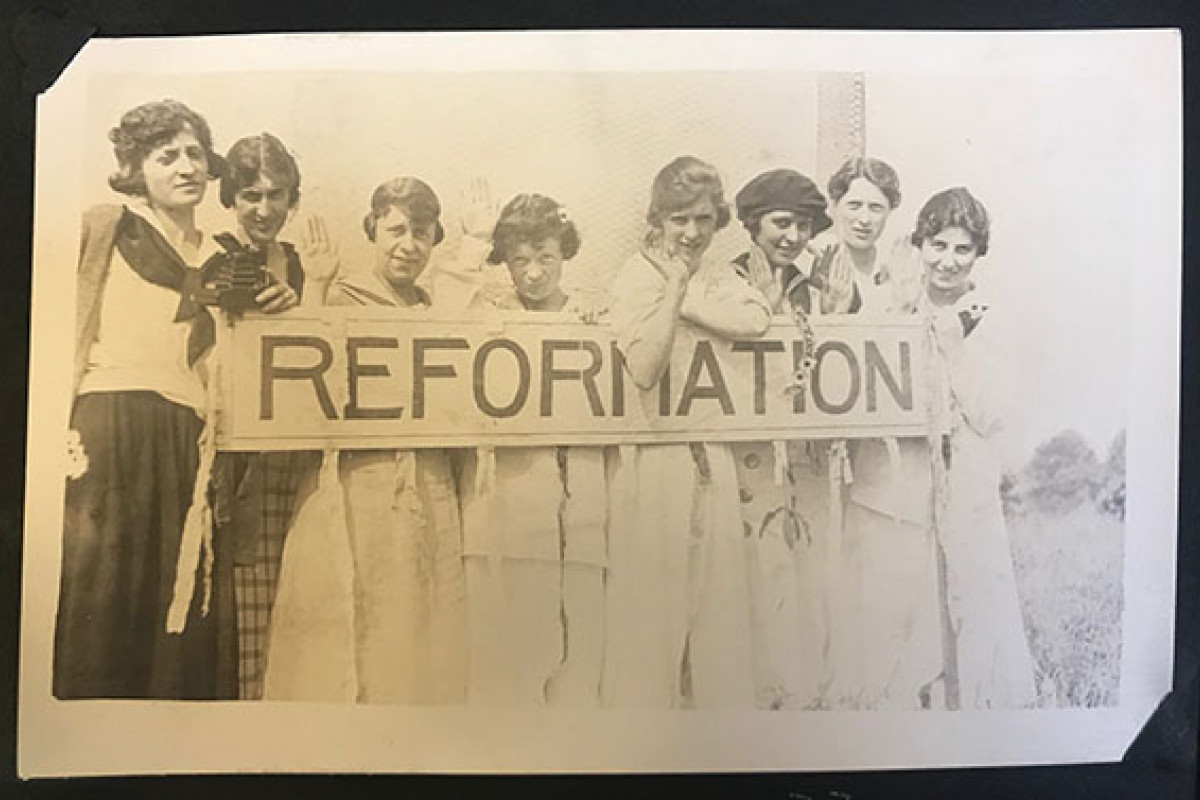 8 women hold a printed sign that says Reformation