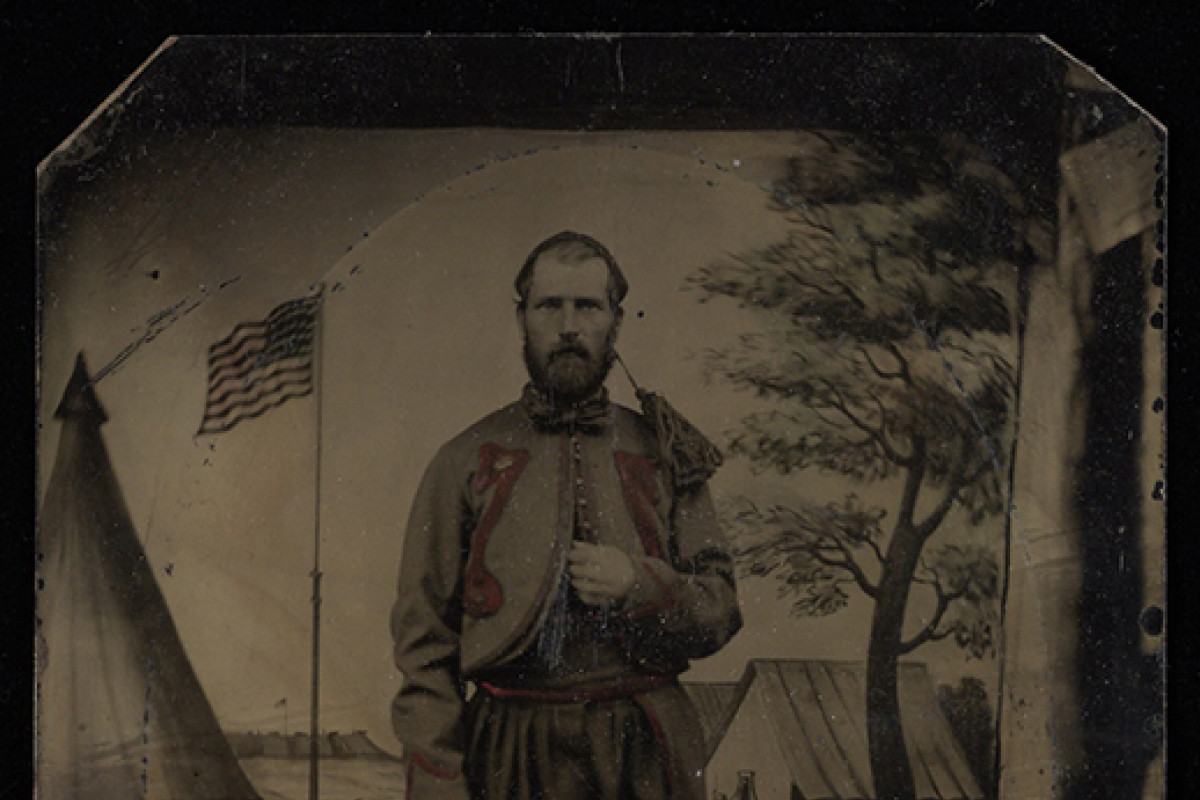 Civil War solider stands at attention in military encampment 