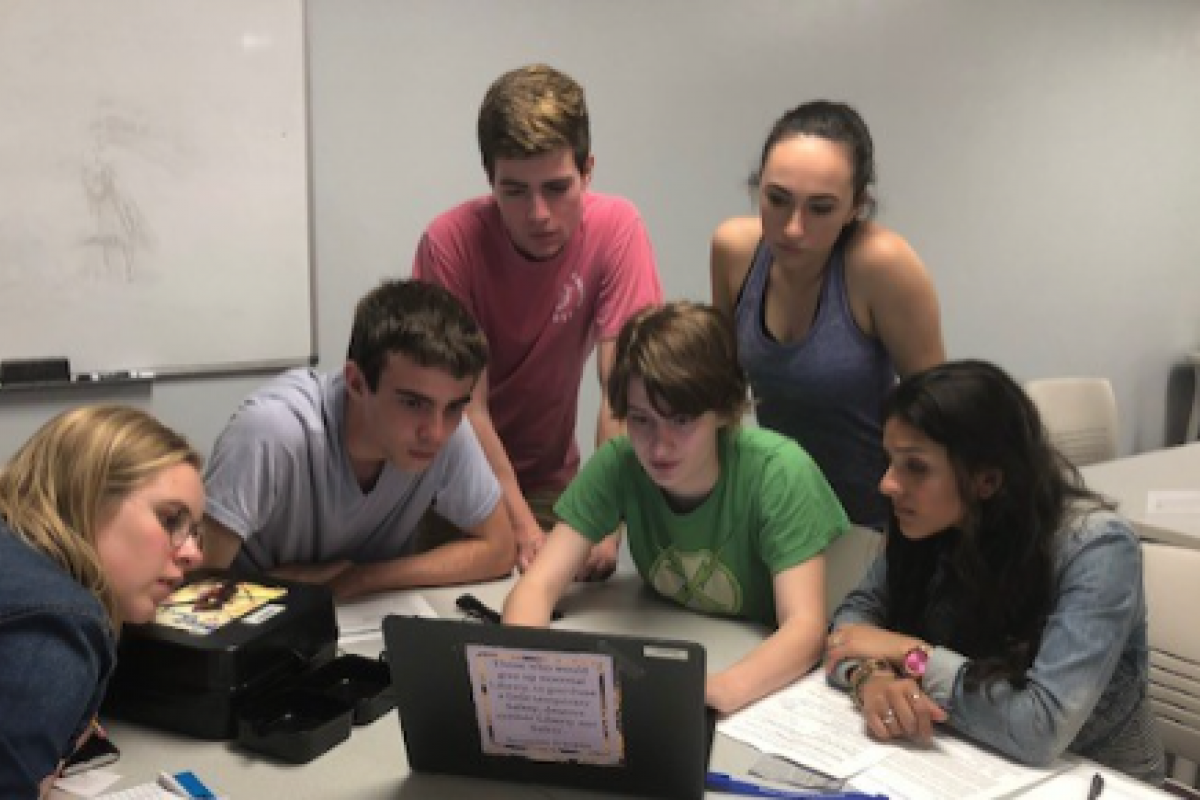 Students gathered around a laptop on a table