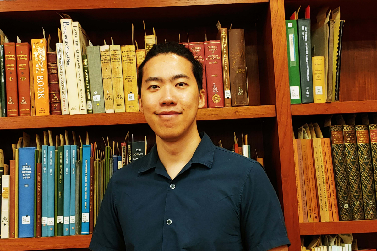 RBSCP Reading Room Graduate Student Assistant Vincent Tanzil standing in front of bookcase