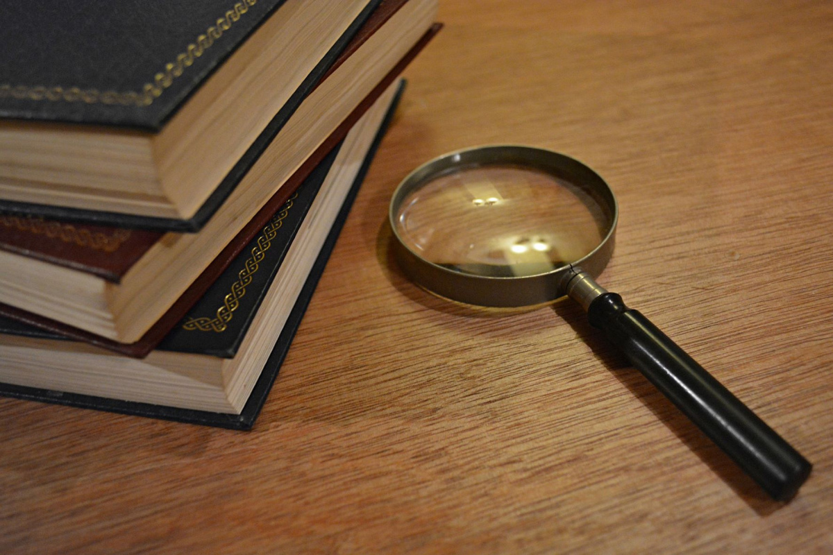 A magnifying glass sitting on a table next to some stacked books