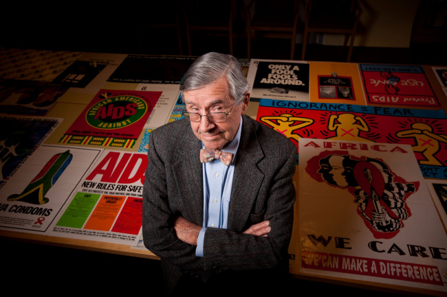 Edward Atwater standing in front of a portion of his collection of AIDS posters