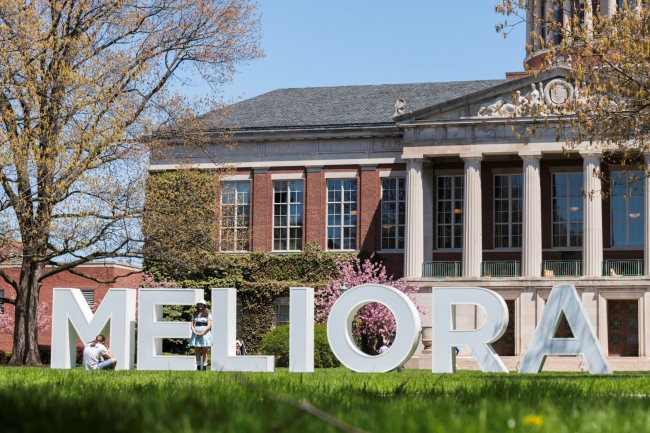 Big white block letters spelling out "Meliora" in front of Rush Rhees Library