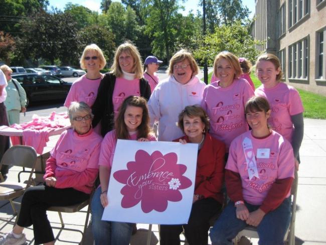 Louise Slaughter sitting among a group of women dressed in pink in support of breast cancer awareness