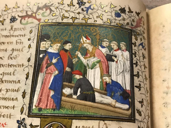 King Darius' dead body is lowered into a coffin. It is surrounded by priests. A priest wearing a miter officiates. Alexander stands to the left of the scene.