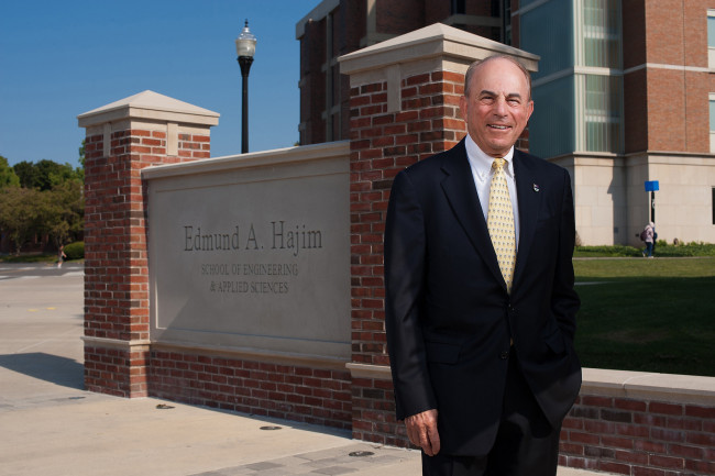 Ed Hajim standing in front of the sign bearing his name near the Hajim quad