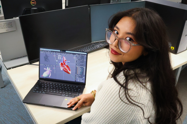 student aadi poses with her 3D modeled heart on a laptop.