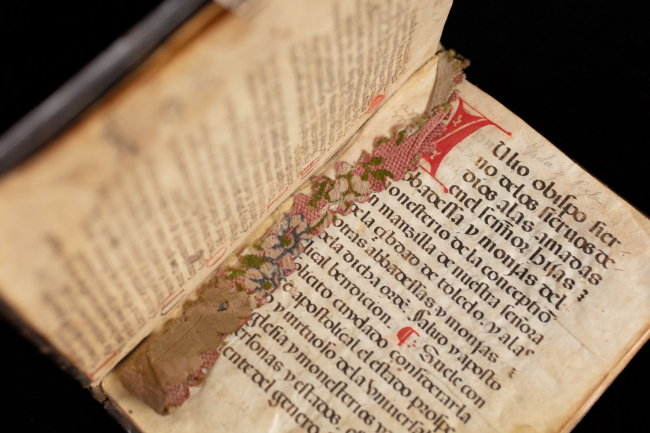 An open manuscript that belonged to a Conceptionist nun; a woven bookmark is draped across the page