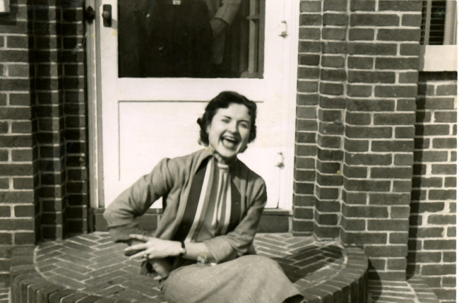 Louise Slaughter as a young woman, sitting and laughing on the stoop of a home believed to be hers in Fairport, NY