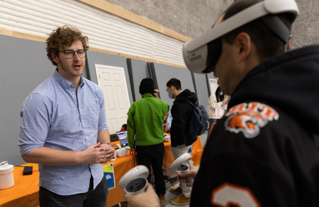 Karp fellow helps a fellow student with using the VR headset. Photo by Quinn Freidenburg
