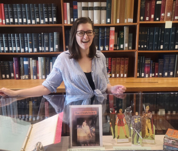 Steffi Delcourt standing behind an Arthurian exhibition she curated