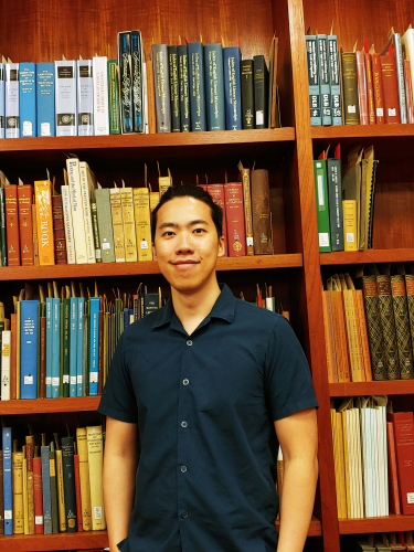 RBSCP Reading Room Graduate Student Assistant Vincent Tanzil standing in front of bookcase