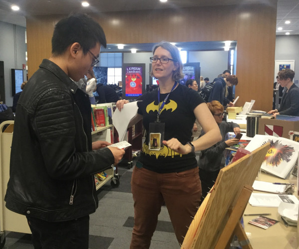 Image showing a woman with a batman shirt on talking to a student during comiccon
