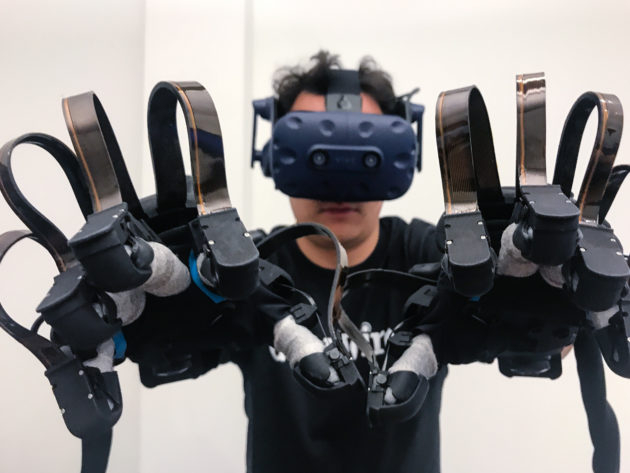 A person in a VR headset and haptic gloves engages with virtual reality.