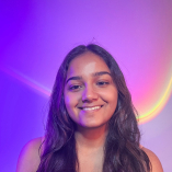 Photo of a person, Gayatry Shetty, smiling in front of a purple shaded background