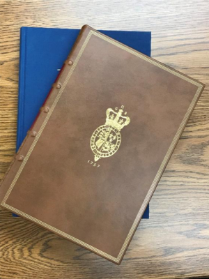 A brown leather bound book on top of a blue slipcover